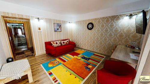 a living room with a red couch and a red chair at Pensiunea Bianca in Botoşani