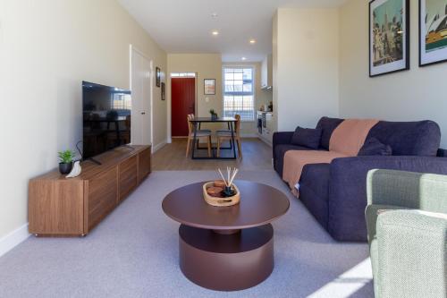 a living room with a couch and a table at Stylish 3BR Escape Parking & Modern Living in Christchurch