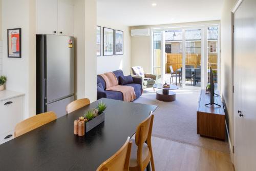 a kitchen and living room with a table and a refrigerator at Stylish 3BR Escape Parking & Modern Living in Christchurch