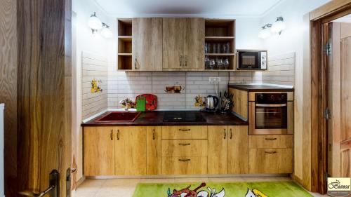 a kitchen with wooden cabinets and a sink at Pensiunea Bianca in Botoşani