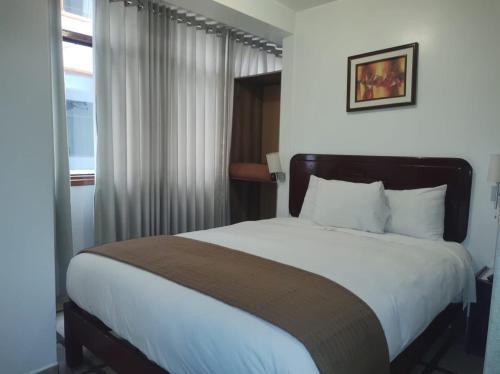 Un dormitorio con una cama grande con sábanas blancas y una ventana. en Selvaterra MachuPicchu, en Machu Picchu