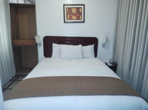 Cama en habitación de hotel con cama blanca grande en Selvaterra MachuPicchu, en Machu Picchu