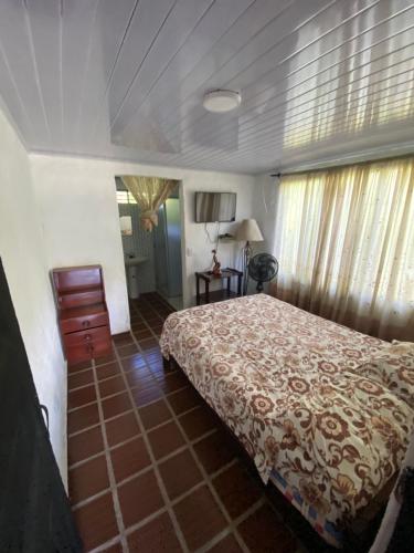 a bedroom with a bed and a dresser and windows at Finca Turística Las Margaritas in Rivera