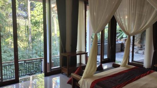 a bedroom with a canopy bed and large windows at Baruna Sari Villa yoga and reatret view jungle in Ubud