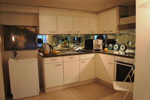 eine kleine Küche mit weißen Schränken und Geräten in der Unterkunft Studio-Appartment Horgen in Horgen