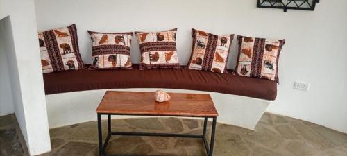 a room with a bed with pillows and a table at Banana House in Watamu