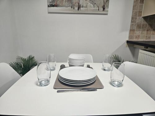 a white table with plates and glasses on it at Cosy 3 Bedroom Bungalow with Private Parking and Rear Garden in Milton Keynes