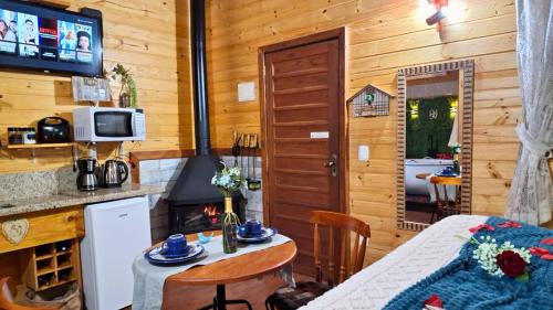 a kitchen with a table and a stove in a cabin at Chalé Temático em Pipa de Vinho - Parada da Pipa Chalés in Canela