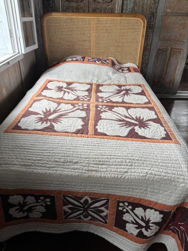 a bed with a quilt with flowers on it at villa Angin in Munggu