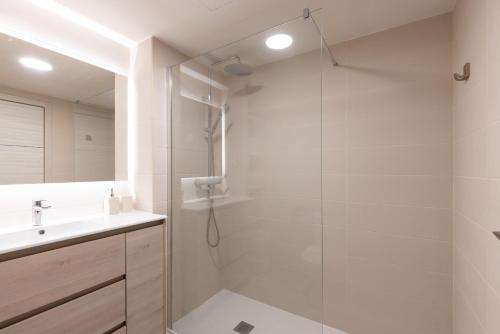 Un baño blanco con ducha y lavabo. en Ancora Planetcostadorada, en Salou