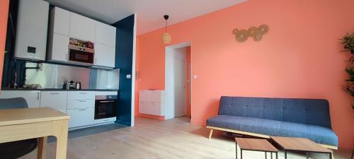 a living room with a blue couch and an orange wall at La perle in Contrexéville