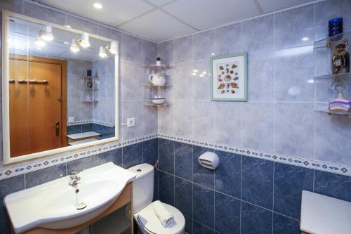Un baño con lavabo, inodoro y espejo. en Egeo Only Families Planetcostadorada, en La Pineda