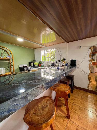 a kitchen with a counter with wooden tables and chairs at Sueños de Oro Corcovado in Sándalo