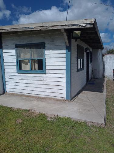 a small white house with a window on a sidewalk at Cabaña La tranquilidad in Santa Teresita