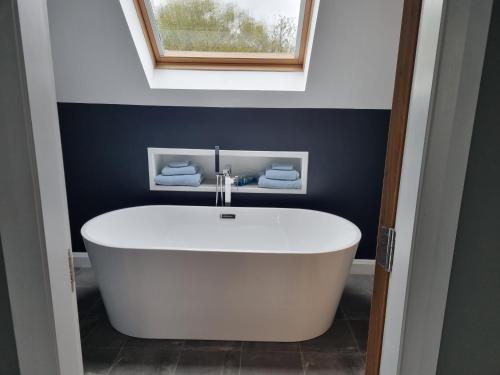 a white bath tub in a bathroom with a window at Causeway Rooms in Ballybogy