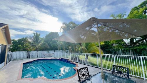 a swimming pool with an umbrella and two chairs at The Poolside Escape Near Beaches in Port Saint Lucie