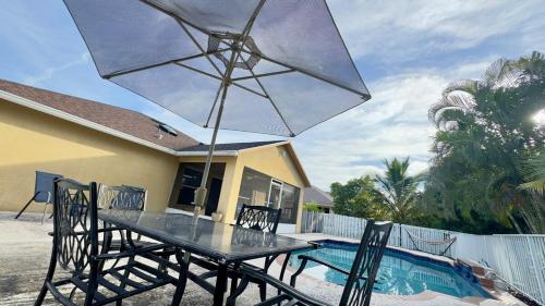 a table with chairs and an umbrella next to a pool at The Poolside Escape Near Beaches in Port Saint Lucie