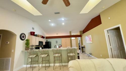 a living room with a kitchen and a bar with stools at The Poolside Escape Near Beaches in Port Saint Lucie