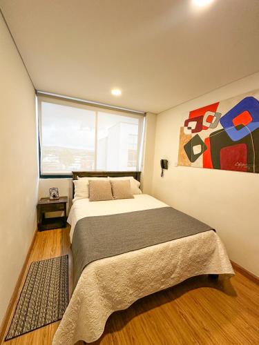 a bedroom with a bed and a large window at Hotel Posada de Santa Elena in Tunja