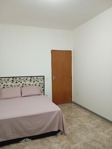 a bedroom with a bed and a wooden door at Marta's house in Peruíbe