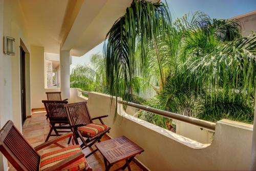 a porch with chairs and a balcony with palm trees at Palmar del Sol by Riviera Maya Suites in Playa del Carmen