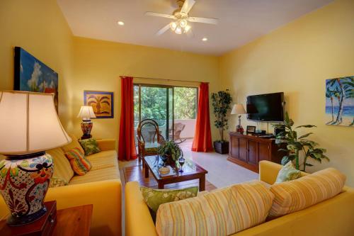 a living room with a couch and a tv at Palmar del Sol by Riviera Maya Suites in Playa del Carmen