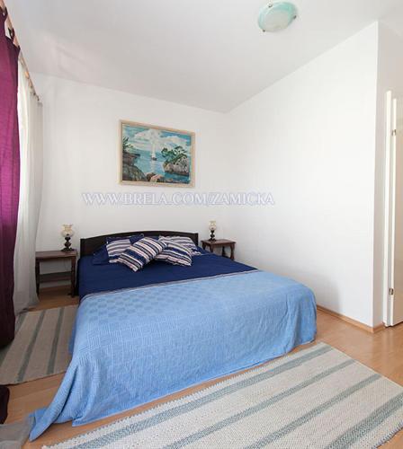 a bedroom with a bed with a blue blanket at Apartments Zamicka in Brela