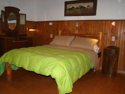 a bedroom with a bed with a green comforter at Hostel San Gregorio in San Gregorio de Polanco