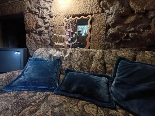 a couch with two blue pillows and a mirror at Orion Guesthouse Telhado in Fundão