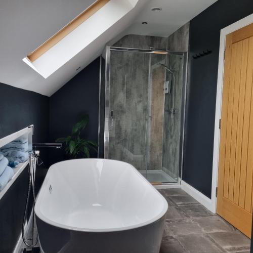 a bathroom with a shower and a white bath tub at Causeway Rooms in Ballybogy