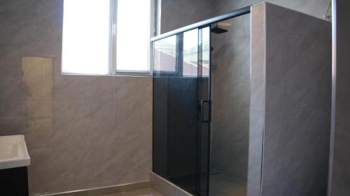 a shower with a glass door in a bathroom at Royal Pool Cottage in Shymkent