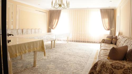 a living room with a couch and a large window at Royal Pool Cottage in Shymkent
