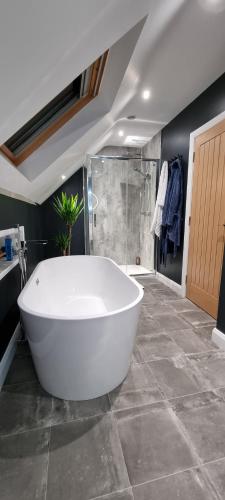 a large white tub in a bathroom with a shower at Causeway Rooms in Ballybogy