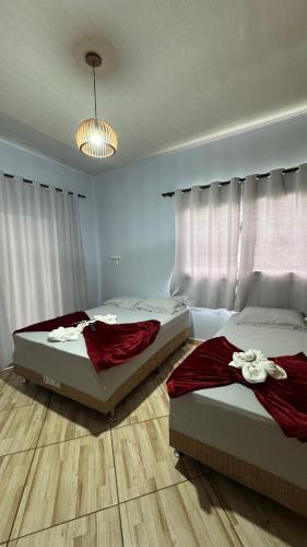 two beds sitting in a bedroom with a window at Pousada Vista Horizonte in Penha