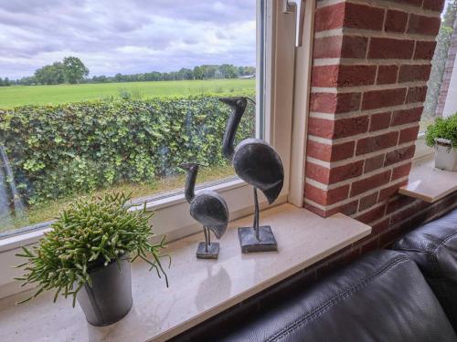 two statues of birds sitting on a window sill at t Achterhoes in Diepenheim