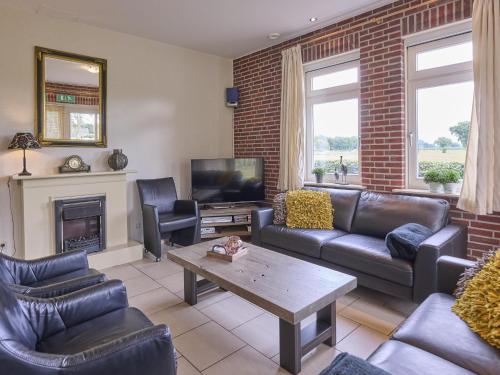 a living room with leather furniture and a fireplace at t Achterhoes in Diepenheim