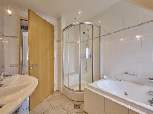 a bathroom with a tub and a shower and a sink at t Achterhoes in Diepenheim