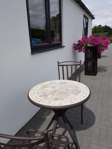 a table and two chairs on a patio with flowers at Stunning Studio2, Banstead with free off st parking in Banstead