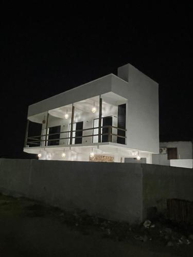 ein großes weißes Haus in der Nacht mit Lichtern in der Unterkunft Taiba House in São Gonçalo do Amarante