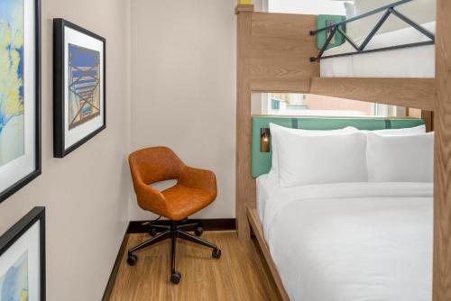 a bedroom with a bed and a chair next to a bunk bed at voco Astoria by IHG in New York