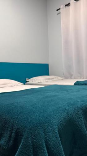 a bed with a blue blanket on top of it at Pousada Vista Horizonte in Penha