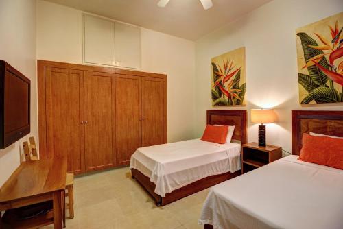 a bedroom with two beds and a flat screen tv at Palmar del Sol by Riviera Maya Suites in Playa del Carmen