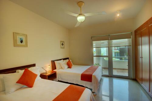 a bedroom with two beds and a ceiling fan at Palmar del Sol by Riviera Maya Suites in Playa del Carmen