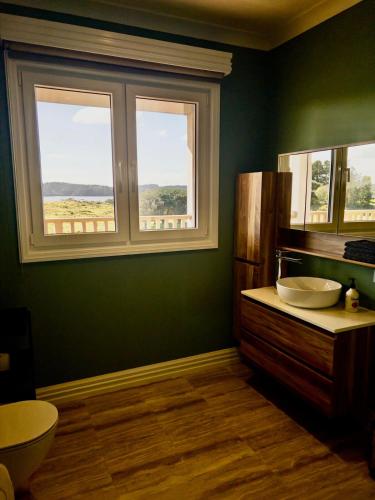 a green bathroom with two sinks and two windows at The View - Over the Bay in Kerikeri
