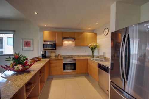 a kitchen with wooden cabinets and a stainless steel refrigerator at Palmar del Sol by Riviera Maya Suites in Playa del Carmen