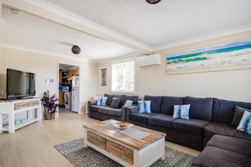 a living room with a couch and a tv at The Perfect Holiday Home in Sussex inlet