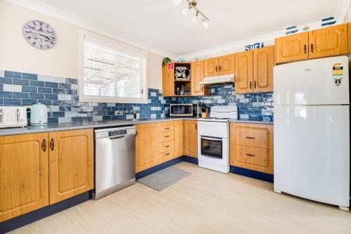 a kitchen with wooden cabinets and white appliances at The Perfect Holiday Home in Sussex inlet
