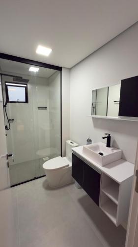 a white bathroom with a toilet and a sink at Loft Moderno no Centro de Blumenau in Blumenau