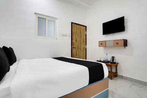 a bedroom with a white bed and a television at Hotel O LAHARI LUXURY ROOMS in Warangal