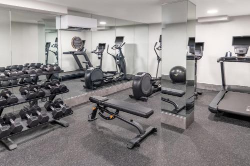 a gym with treadmills and exercise bikes and a mirror at voco Astoria by IHG in New York